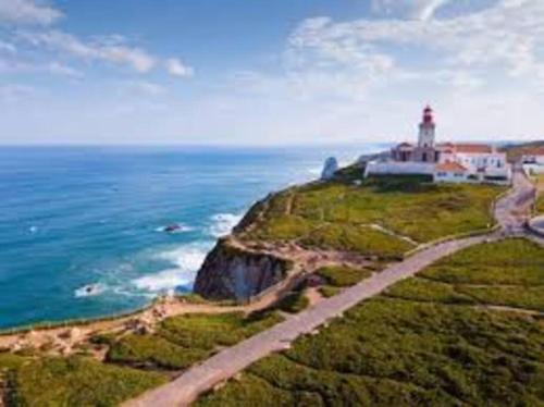 a lighthouse on a cliff next to the ocean at Enjoy Beloura! in Sintra