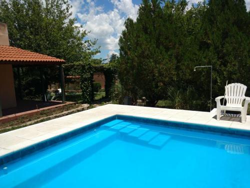 una piscina azul con una silla blanca y una silla istg en Mirasoles Hotel, en Mina Clavero