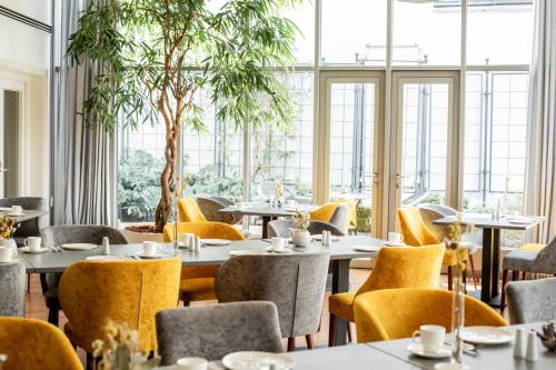 un restaurant avec des tables, des chaises et des fenêtres dans l'établissement Altstadthotel Messerschmitt, à Bamberg