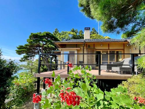 ein Haus mit einer Terrasse mit roten Blumen in der Unterkunft Hitachinaka Villa DAN - ひたちなか 暖 - in Hitachinaka