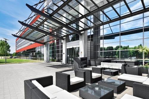 um pátio com cadeiras e mesas num edifício em Novina Hotel Herzogenaurach Herzo-Base em Herzogenaurach