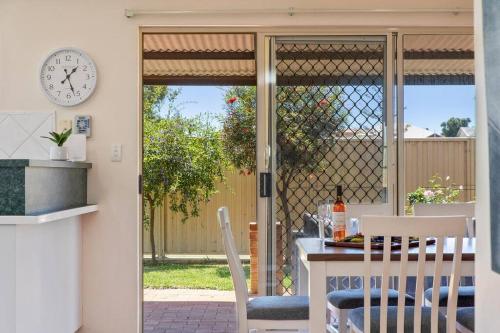 a dining room with a table and a clock on the wall at Light & bright Falcon Bay family holiday escape in Mandurah