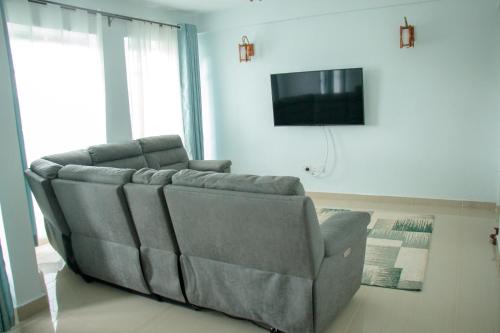 ein Sofa im Wohnzimmer mit TV in der Unterkunft Zoe Homes 1br and 2br Apartment Greypoint 406 in Kericho