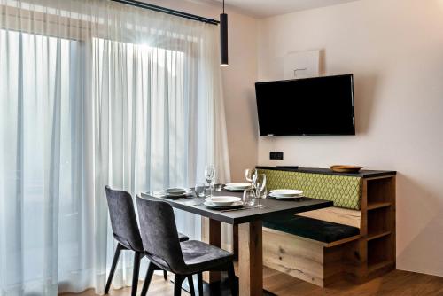 een eetkamer met een tafel en stoelen en een televisie bij Apartment Bullaccia Stlarida in Ortisei