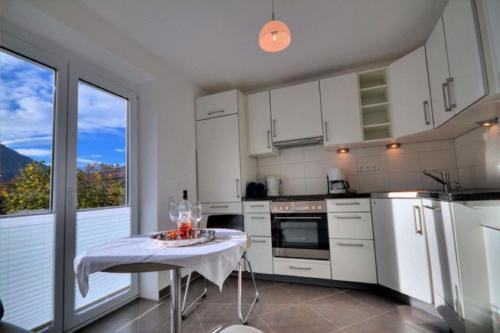 - une cuisine avec des placards blancs et une table avec des verres dans l'établissement Kaufhold Ferienwohnung, à Immenstadt