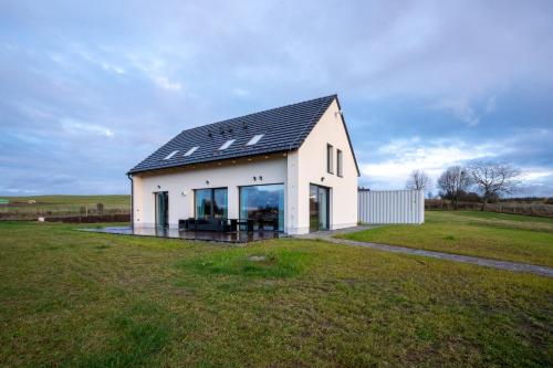 een wit huis met een zwart dak in een veld bij Vila Jestřábí s výhledem na Lipno, klidná lokalita in Černá v Pošumaví