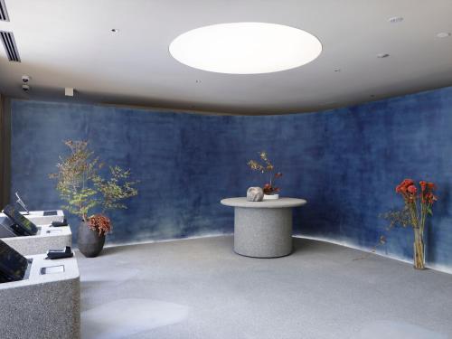 a room with a blue wall with a table and flowers at SOKI Kanazawa in Kanazawa