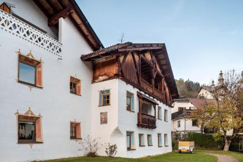 a white building with a wooden roof at Cesa Valeria App Monika in Ortisei