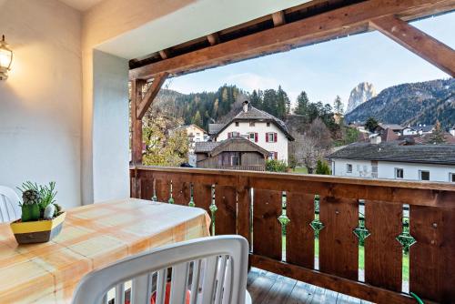 a balcony with a table and chairs and a large window at Cesa Valeria App Monika in Ortisei