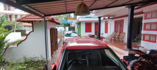 una macchina rossa parcheggiata di fronte a una casa di RED LION a Varkala