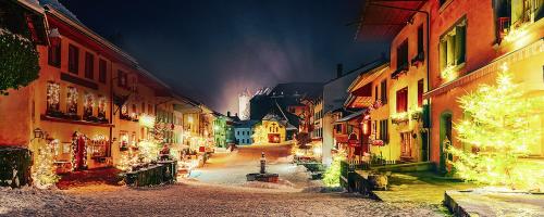 eine Stadtstraße mit Weihnachtslichtern und einem Weihnachtsbaum in der Unterkunft Hôtel de Ville in Gruyères