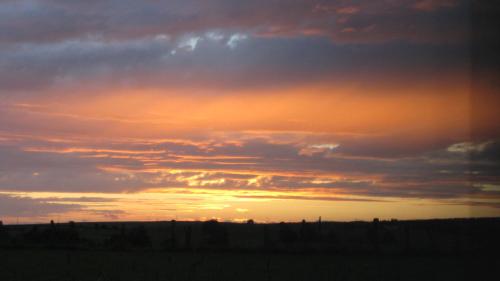 zachód słońca nad polem z pochmurnym niebem w obiekcie La course du soleil w mieście Saint-Hubert