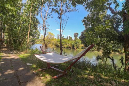 a chair sitting on the side of a river at StayVista at Firefly By The River with Breakfast in Kushālnagar