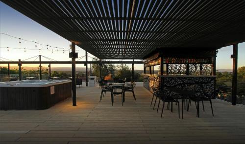 un patio avec des tables et des chaises et un bain à remous dans l'établissement Pinares Panorama Suites & Spa, à Villa Carlos Paz