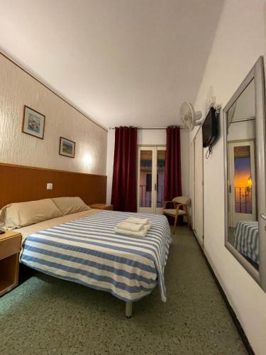 - une chambre dotée d'un lit avec une couverture rayée bleue et blanche dans l'établissement P&R hostals Maria Rosa, à Tossa de Mar