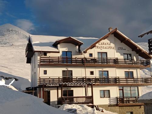 een gebouw bovenop een met sneeuw bedekte berg bij Cabana Transalpina in Ranca