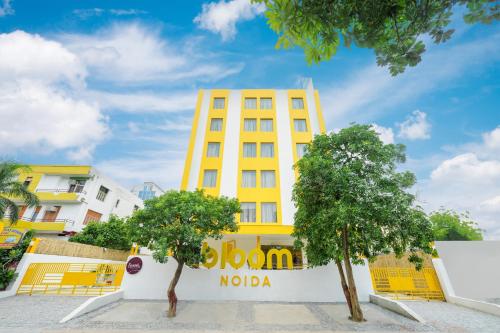 a yellow building with trees in front of it at Bloom Hotel - Sector 62 in Noida