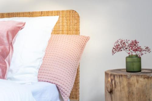 ein Bett mit einem Kissen und einer Vase aus Blumen auf einem Tisch in der Unterkunft ROOM SAUVAGE in Vincennes