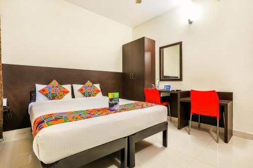 een slaapkamer met een bed en een bureau met rode stoelen bij FabHotel RMS Comforts - Nr Yeshwantpur Railway Station in Bangalore