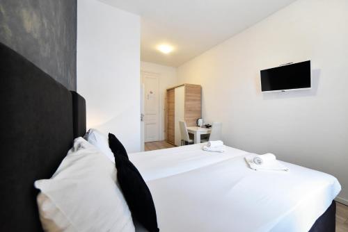 una camera con letto bianco e TV a parete di Virtus Apartments and Rooms with Free Private Parking a Zagabria