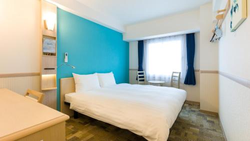 Habitación de hotel con cama y pared azul en Toyoko Inn Chofu Keio sen Fuda eki, en Chofu