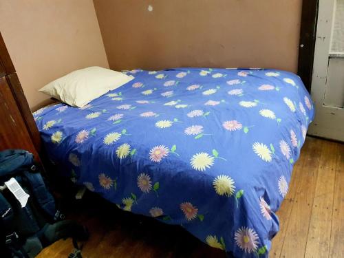 een bed met een blauw dekbed met bloemen erop bij St Kilda East backpackers' hostel in Melbourne