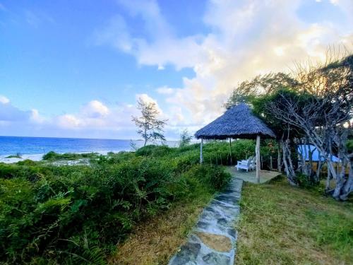 a path to a beach with a gazebo and the ocean at Watamu Beach Cottages in Watamu