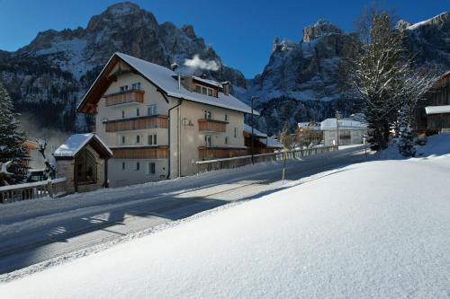 budynek w śniegu z górami w tle w obiekcie Piz Alpin B&B w mieście Colfosco