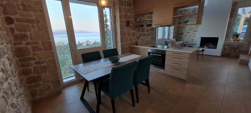 cocina con mesa y sillas y ventana grande en Πέτρα, Ελιά και Λεβάντα, en Tolo