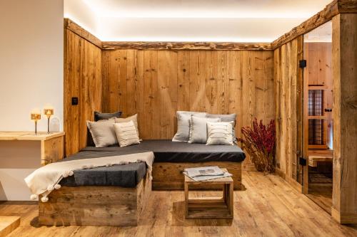 una camera da letto con una parete in legno, un letto e un tavolo di Bellevue Bruneck - Suites & Lofts a Brunico