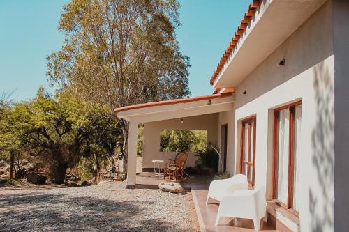 un patio de una casa con sillas blancas y árboles en EL PEDREGAL Casa en Cafayate, en Cafayate