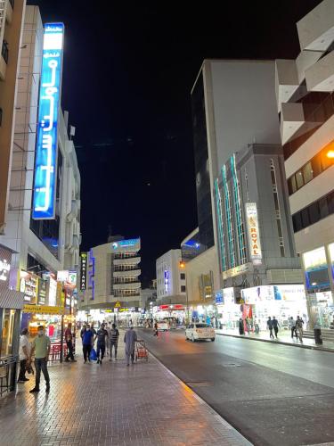 eine Gruppe von Menschen, die nachts eine Stadtstraße entlang laufen in der Unterkunft MOUNT SINA HOTEL By AURA in Dubai