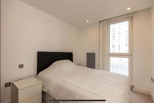 a white bedroom with a bed and a window at Arena Apartment in Manchester