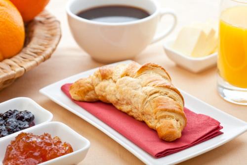 uma mesa com um prato de croissants e uma chávena de café em Hotel Colonial Blanco em Santo Domingo