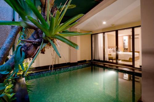 una piscina en una habitación de hotel con una planta en Cross Vibe Paasha Atelier Bali Kuta en Kuta