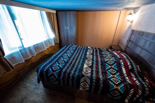 a bedroom with a bed and a large window at Evdo Apartments Loft2 Wooden House in Gudauri