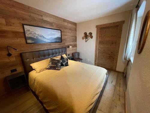 - une chambre avec un lit et un mur en bois dans l'établissement Apartment Gran Baita Sauze d'Oulx, à Sauze dʼOulx