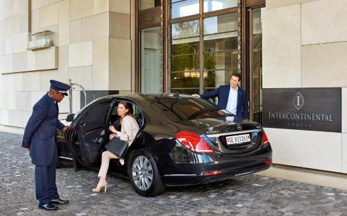 um homem e uma mulher a entrar num carro à porta de um edifício em InterContinental Genève, an IHG Hotel em Genebra