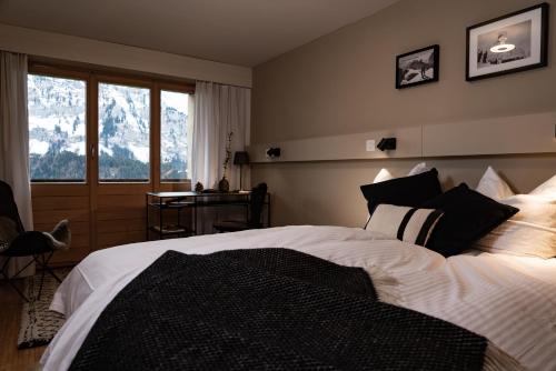 Schlafzimmer mit einem Bett, einem Schreibtisch und einem Fenster in der Unterkunft VILLA HUNDERT Boutique Mountainscape in Engelberg