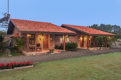 uma pequena casa com flores vermelhas em frente em SaffronStays Lake House Marigold, Nashik - rustic cottages with private plunge pool em Nashik