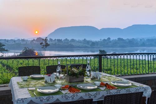 uma mesa de jantar com vista para um rio em SaffronStays Lake House Marigold, Nashik - rustic cottages with private plunge pool em Nashik