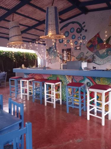 um restaurante com um bar com bancos coloridos em Il Triangolo Hostel em Las Galeras