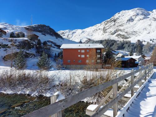 ein rotes Gebäude im Schnee neben einem Zaun in der Unterkunft Corn Alv 13 in Bivio