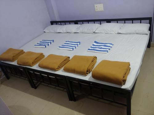 un letto con lenzuola bianche e blu e cuscini marroni di Ambai Guest House a Kolhapur