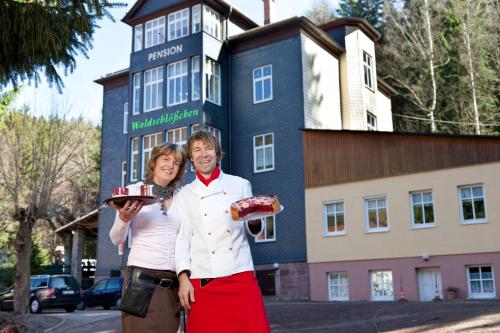 um homem e uma mulher segurando um bolo em frente a um prédio em Pension Waldschlösschen em Friedrichroda