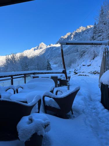 Chalet Galadhrim Chamonix Mont Blanc Valley في لي أوش: مجموعة من المقاعد مغطاة بالثلج مع جبال في الخلفية