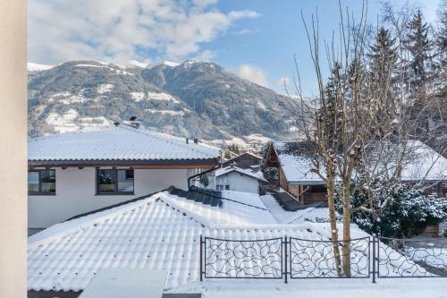 uma casa coberta de neve com montanhas ao fundo em Apart Joachim em Fügen