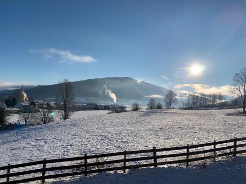 a snow covered field with a fence in front of a mountain at Appartement Aigner in Mauterndorf