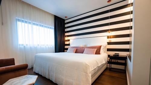 a bedroom with a white bed and a striped wall at Hills Hotel Lisboa in Lisbon