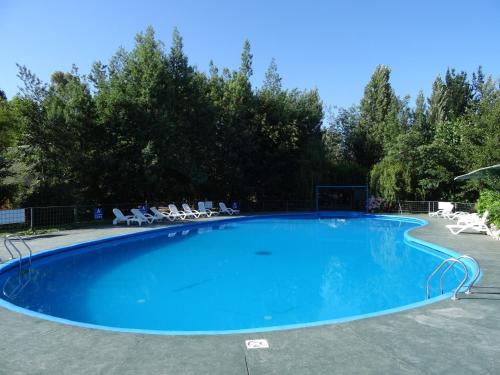 uma grande piscina azul com cadeiras e árvores em Cabañas Parque Salto del Laja em El Manzano